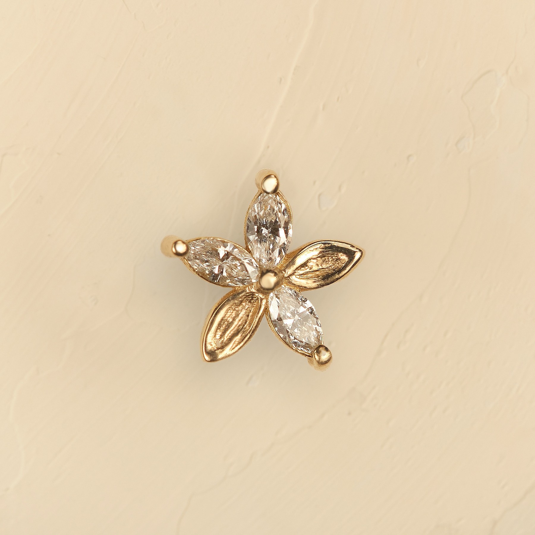 Gold floral earring on a cream background